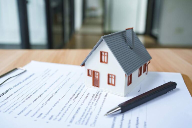 A person examining property documents with maps, deeds, and paperwork laid out on a desk.