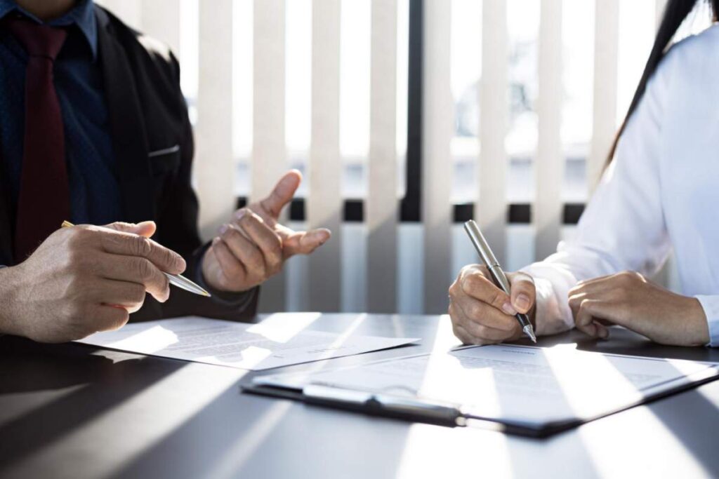 A homebuyer reviews a title report beside property records and closing documents on a table.