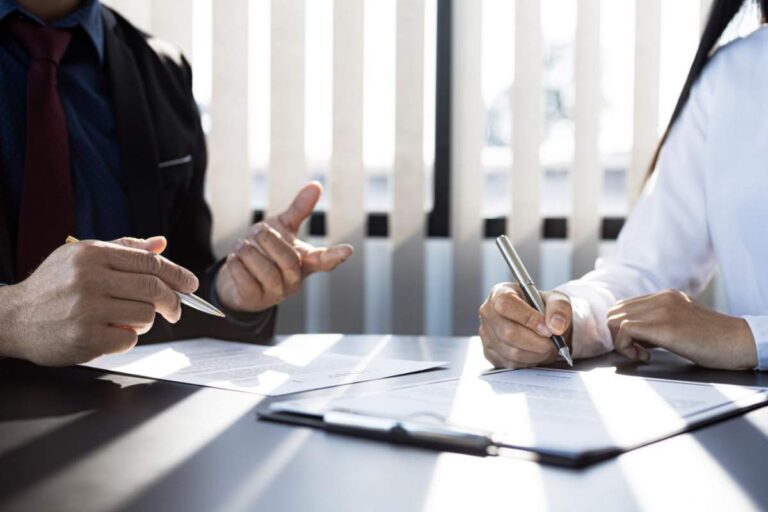 A homebuyer reviews a title report beside property records and closing documents on a table.